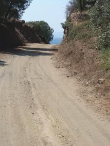 a dirt road with the ocean in the distance at Olive Bay Hilltop Apartments Ammouliani in Ammouliani