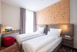 um quarto de hotel com duas camas e um banco vermelho em Amaro Hotel em Bergkirchen