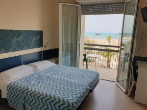 a bedroom with a bed and a balcony with the ocean at Hotel Giannini in Rimini