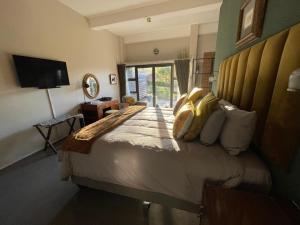 a bedroom with a large bed with yellow pillows at Bramasole Guesthouse in Magoebaskloof