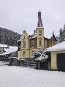 a large yellow house with a tower in the snow at Apartmán Kraslice in Kraslice