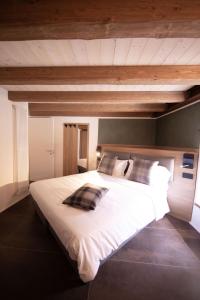 a large white bed in a bedroom with wooden ceilings at Bhotanica - ospitalità e natura in Aosta