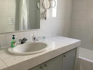 ein Badezimmer mit einem weißen Waschbecken und einem Spiegel in der Unterkunft AGIA PARASKEVI appartement près du métro in Athen