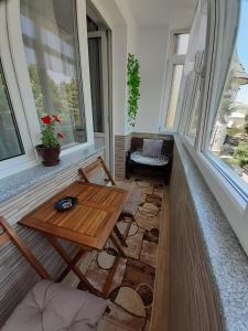 a balcony with a table and a bench and windows at Apartament Ultra Central Marly Gura Humorului in Gura Humorului