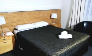 a hotel room with a bed with a hat on it at City Park Motel and Apartments in Wagga Wagga