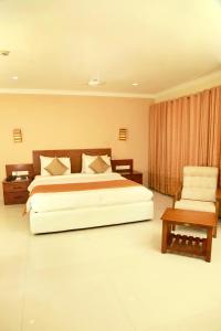 1 dormitorio con 1 cama grande y 1 silla en KTDC Grand Chaithram en Thiruvananthapuram