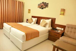 a bedroom with a large bed and a chair at KTDC Grand Chaithram in Trivandrum