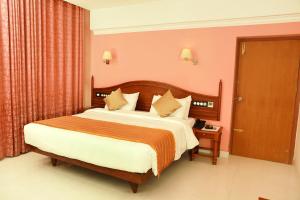 ein Schlafzimmer mit einem großen Bett in einem rosa Zimmer in der Unterkunft KTDC Grand Chaithram in Thiruvananthapuram