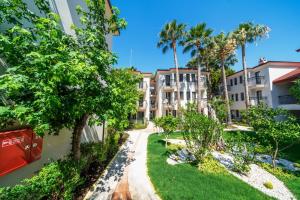 an apartment complex with palm trees and a walkway at Sundia By Liberty Oludeniz in Oludeniz