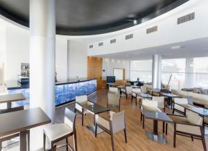 a dining room with tables and chairs and windows at TRYP by Wyndham Porto Expo Hotel in Leça da Palmeira