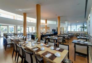 a restaurant with wooden tables and chairs and windows at TRYP by Wyndham Porto Expo Hotel in Leça da Palmeira