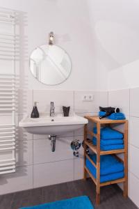 La salle de bains est pourvue d'un lavabo, d'un miroir et de serviettes bleues. dans l'établissement Ferienwohnungen Schwabenhof, à Schramberg