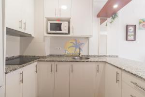 a white kitchen with a sink and a microwave at NOVELTY IBERPLAYA in Salou