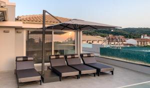 a group of chairs sitting under an umbrella on a balcony at Balia Suites in Acharavi
