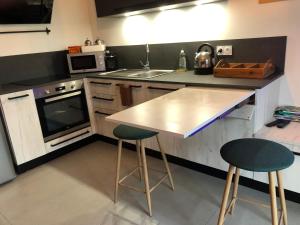 a kitchen with a counter and two bar stools at LE BEL AIR in Pugny-Chatenod