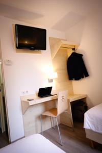 a room with a desk with a bed and a laptop at Kyriad Direct Perpignan Nord - Aéroport in Rivesaltes