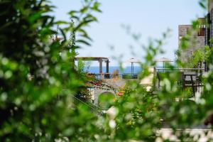 a garden with flowers and a bridge in the background at Margo Beach Hotel in Gythio
