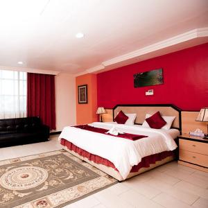فندق مايفير في دار السلام: غرفة نوم بسرير كبير وجدار احمر