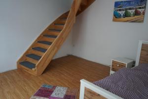 Cette chambre est dotée d'un escalier en bois et d'un lit. dans l'établissement Gästewohnung Holzheim, à Pohlheim