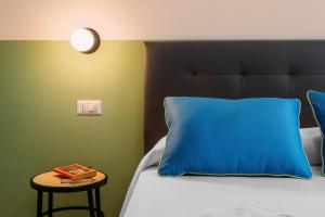 a bed with a blue pillow and a side table at Sorrento Colors&Suites in Sorrento