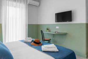 a bedroom with a bed with towels and a hat on it at Sorrento Colors&Suites in Sorrento