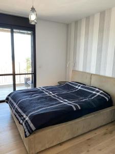 a bedroom with a bed with a blue blanket at Bat Galim Luxury balcony SEA view Nearby The Beach for Doctor's in Haifa