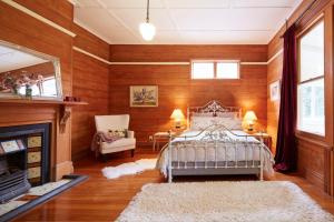Kaituna Valley Homestead في Little River: غرفة نوم بجدران خشبية وسرير ومدفأة