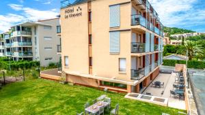 an apartment building with a lawn in front of it at Hotel Le Virevent in Saint-Raphaël