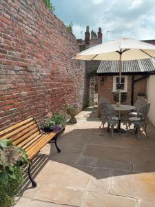 a patio with a wooden bench and an umbrella at Delighful self catering in the heart of Glastonbury in Glastonbury