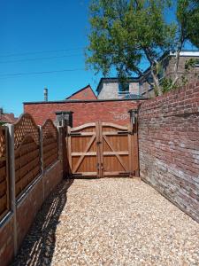 a wooden gate in a brick wall with a driveway at Delighful self catering in the heart of Glastonbury in Glastonbury