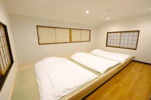 由布市にあるiORi Yufuin ーVacation House With Private Hot Springの白いシーツと窓が備わるドミトリールームのベッド1台分です。