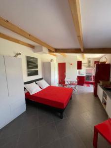 a bedroom with a red bed and a kitchen at Nuit calme sur domaine in Calcatoggio