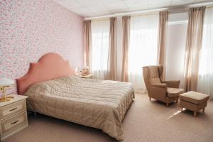 a bedroom with a bed and a chair at Palisad Hotel in Vologda