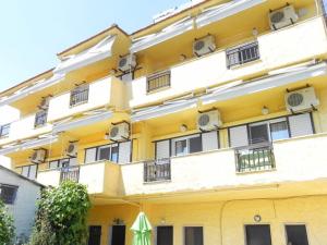 un edificio amarillo con ventanas y una sombrilla verde en Bellos Apartments, en Nea Skioni