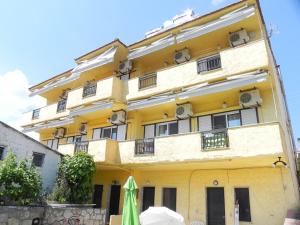 a yellow building with an umbrella in front of it at Bellos Apartments in Nea Skioni