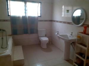 y baño con aseo, lavabo y espejo. en Impeccable 2-Bed Apartment in Kumasi Ashanti, 