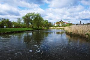 un río con árboles y un edificio de fondo en Apartament Maria, en Supraśl