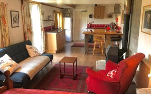 a living room with a couch and a kitchen at Holifield Farm Hostel & Community Project in Helston