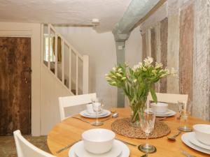 una mesa de comedor con un jarrón de flores. en The Hideaway at Burrow Hill, en Ottery St Mary