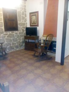 sala de estar con silla y TV en Casa Rural del Médico I y II, en Herradón de Pinares