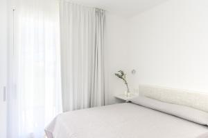 a white bedroom with a bed and a window at Capo Falcone Charming Apartments in Stintino