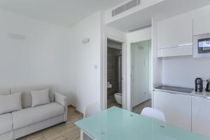 a white living room with a couch and a kitchen at Capo Falcone Charming Apartments in Stintino