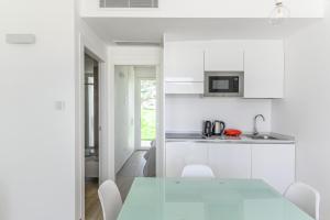 a white kitchen with a table and chairs at Capo Falcone Charming Apartments in Stintino