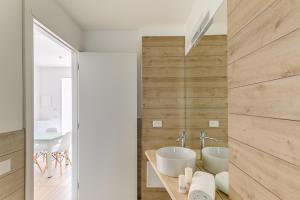 a bathroom with two white sinks and a wall with wood at Capo Falcone Charming Apartments in Stintino