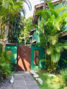 a house with a green fence and palm trees at Waimea Flats Maresias in Maresias