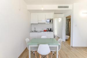 a kitchen with a green table and white chairs at Capo Falcone Charming Apartments in Stintino