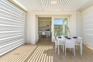 a dining room with a table and white chairs at Capo Falcone Charming Apartments in Stintino