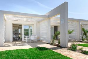 a white house with a patio with a table at Capo Falcone Charming Apartments in Stintino