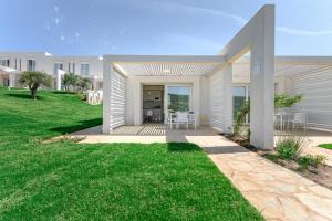 a home with a patio and green grass at Capo Falcone Charming Apartments in Stintino