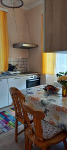 eine Küche mit einem Tisch und Stühlen sowie eine Küche mit gelben Vorhängen in der Unterkunft Da Tizzi in Deutschlandsberg